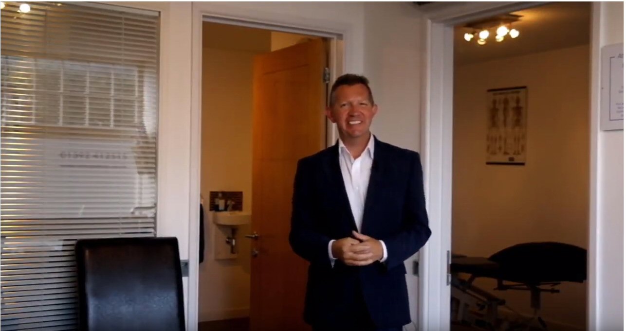 Adrian standing in a clinic reception area, showcasing his dedication to healthcare automation